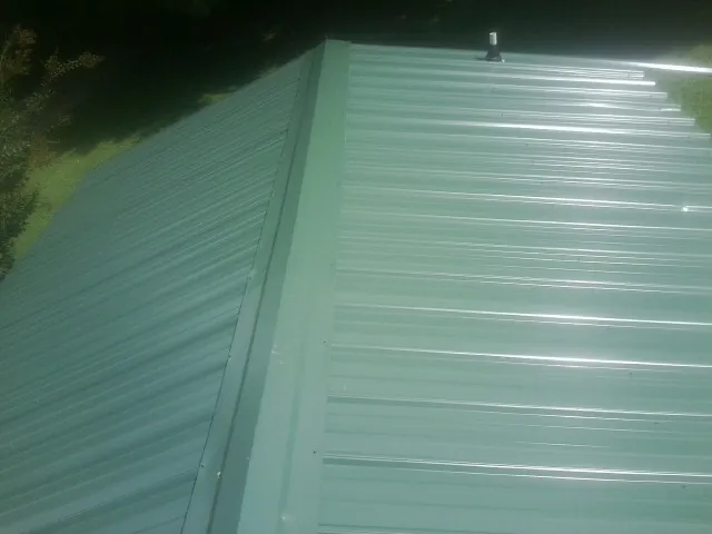 New green metal panels meeting at the ridge of a roof — Flat Roof Repair work by our crew in Las Animas