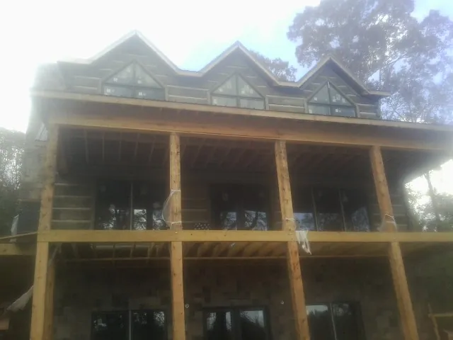 Dormers and porch framing on a large log home under construction — Roof Coating work by our crew in Las Animas