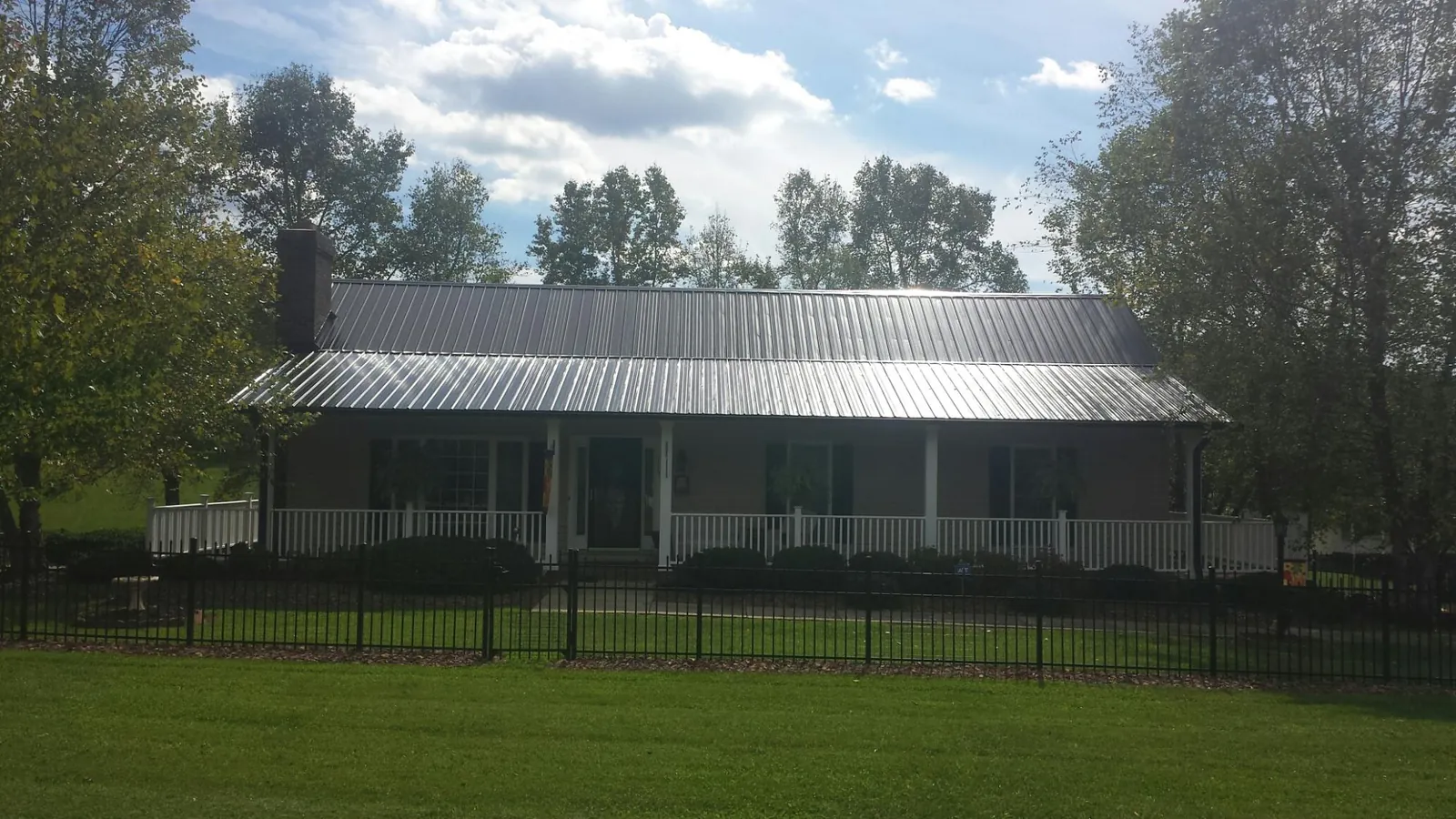Gray metal roof on a brick ranch with a full width front porch — Gutter Guard Installation work by our crew in Las Animas