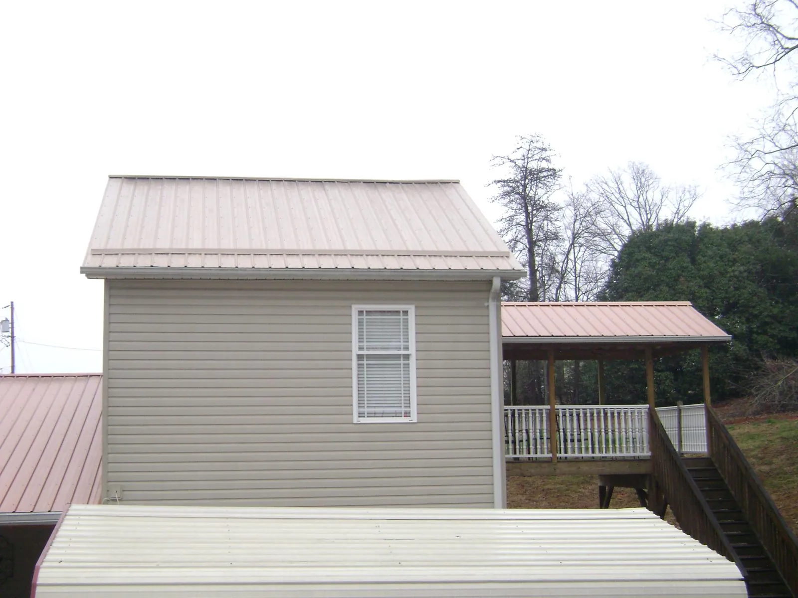 Tan metal roofs on a two story addition and attached porch, from a Roof Replacement job in Las Animas