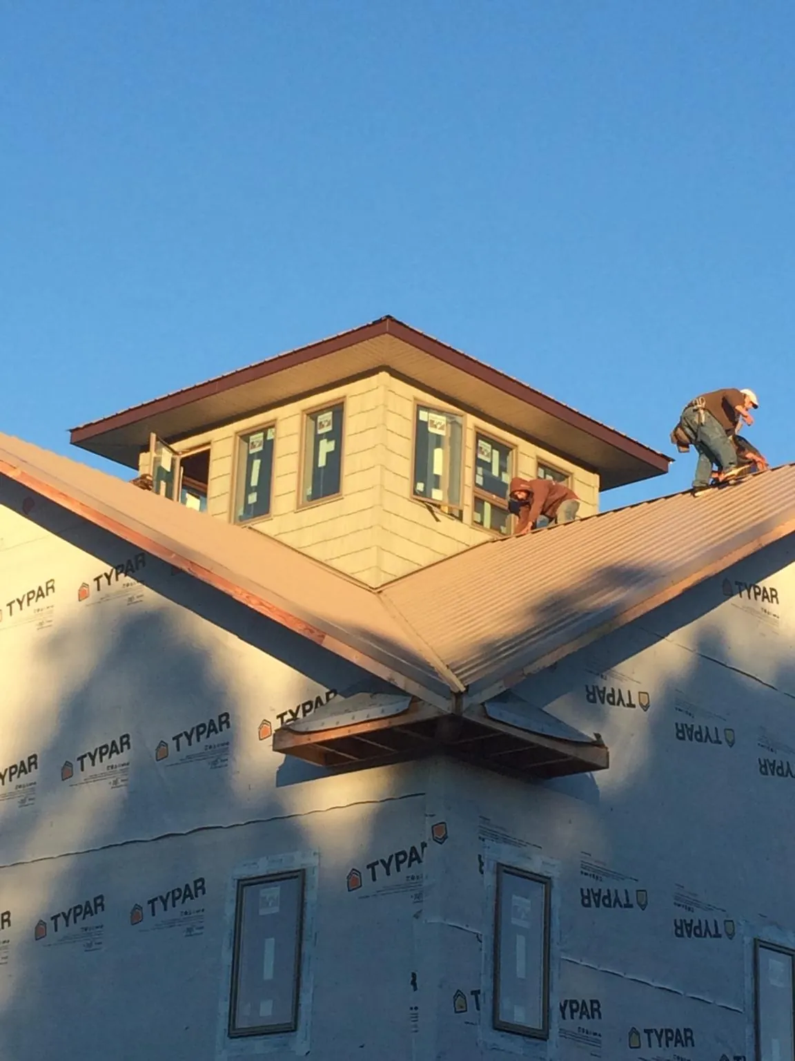 Roofers working around a rooftop cupola on a new metal roof at sunset — Roof Waterproofing in Las Animas by Roofing Brothers
